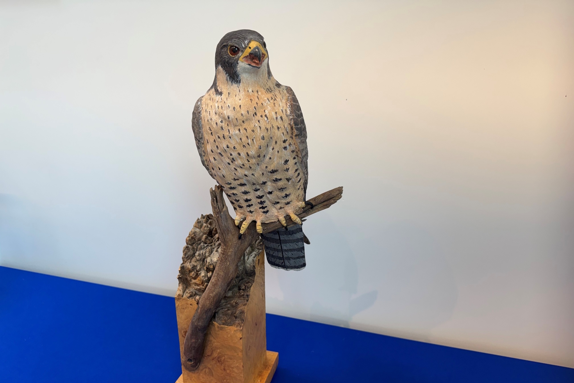 Sculpture depicting a Peregrine Falcon perched on a small branch