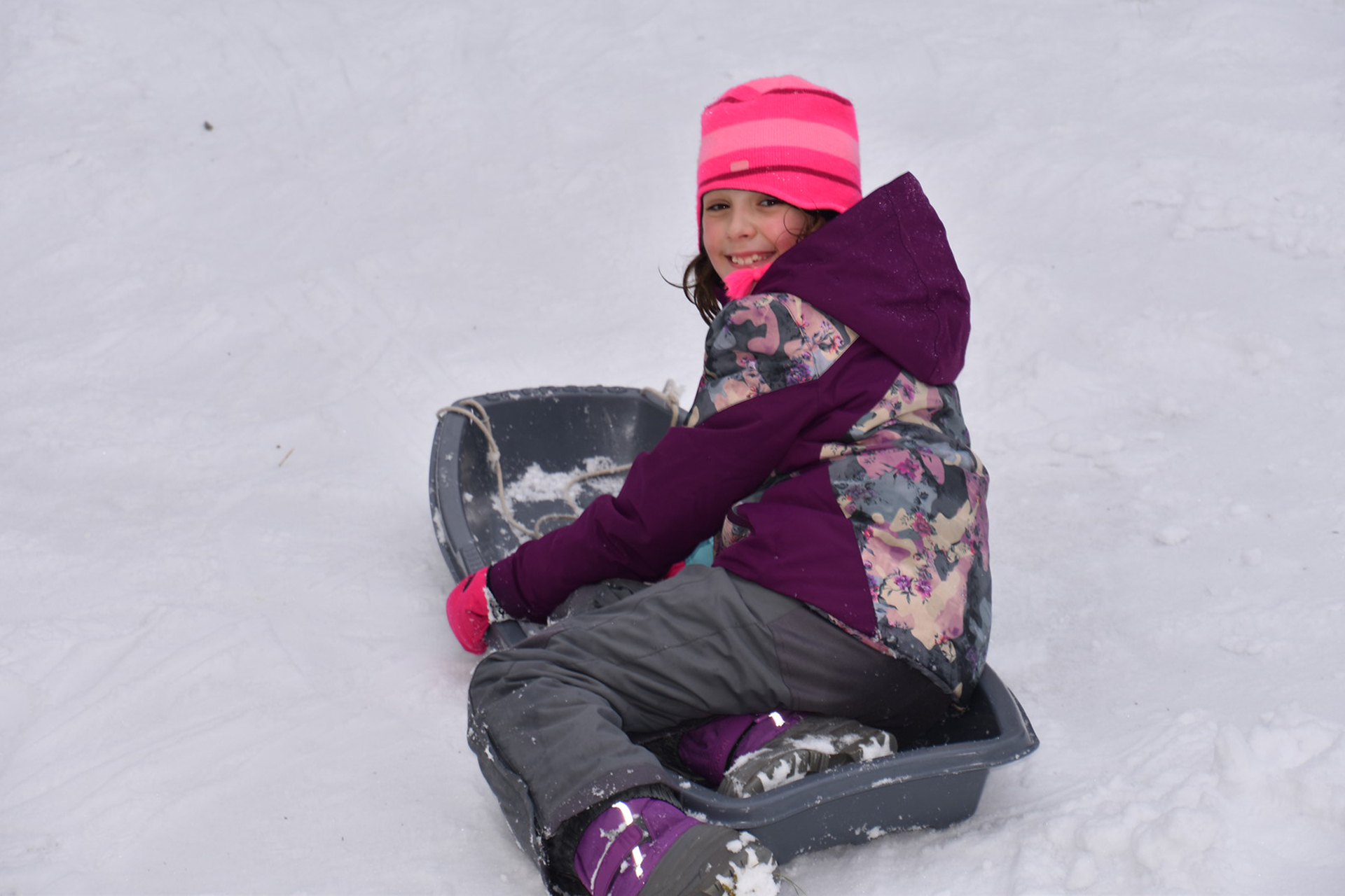 Girl in pink snow gear sledding