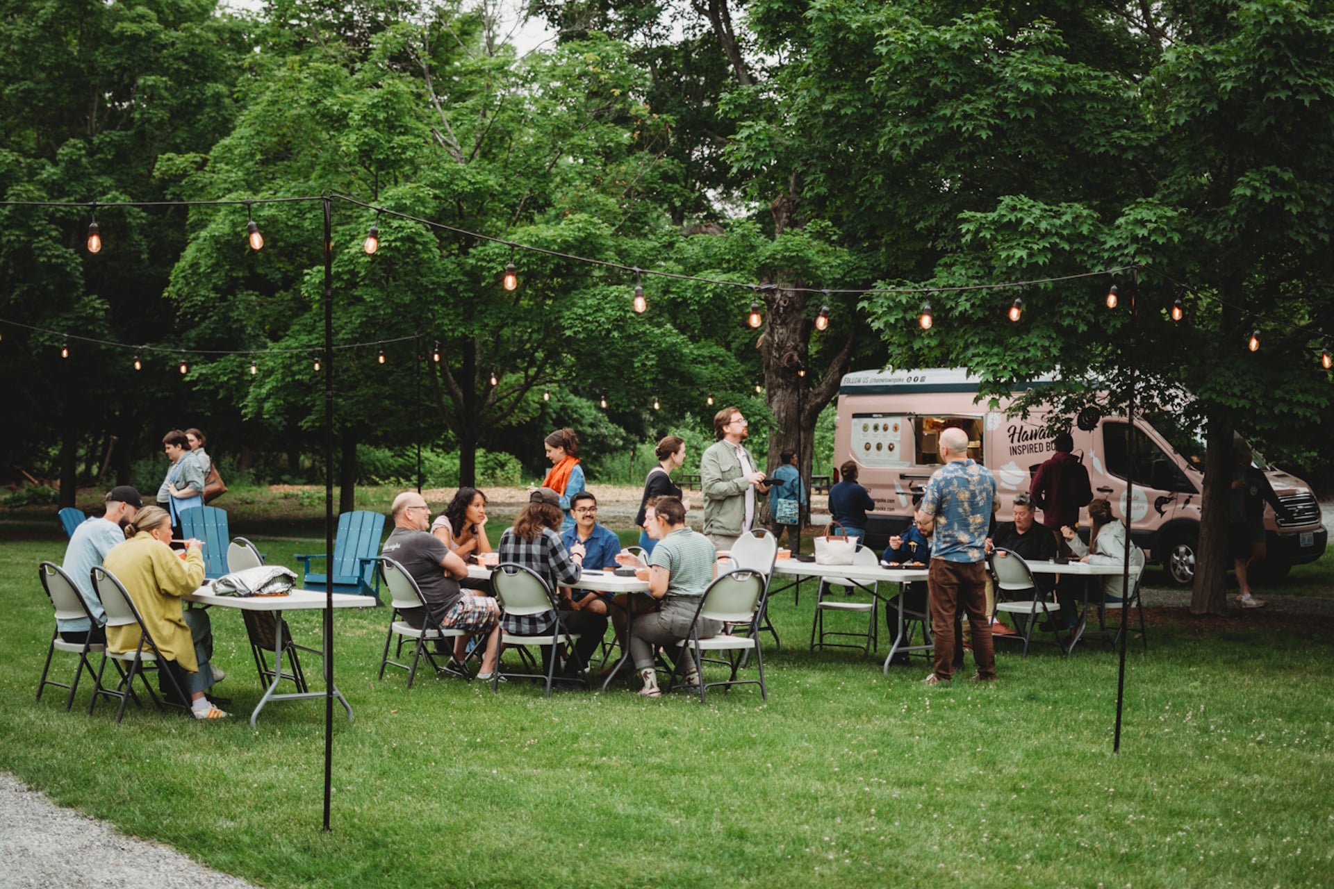 People milling about tables with a food truck in the background