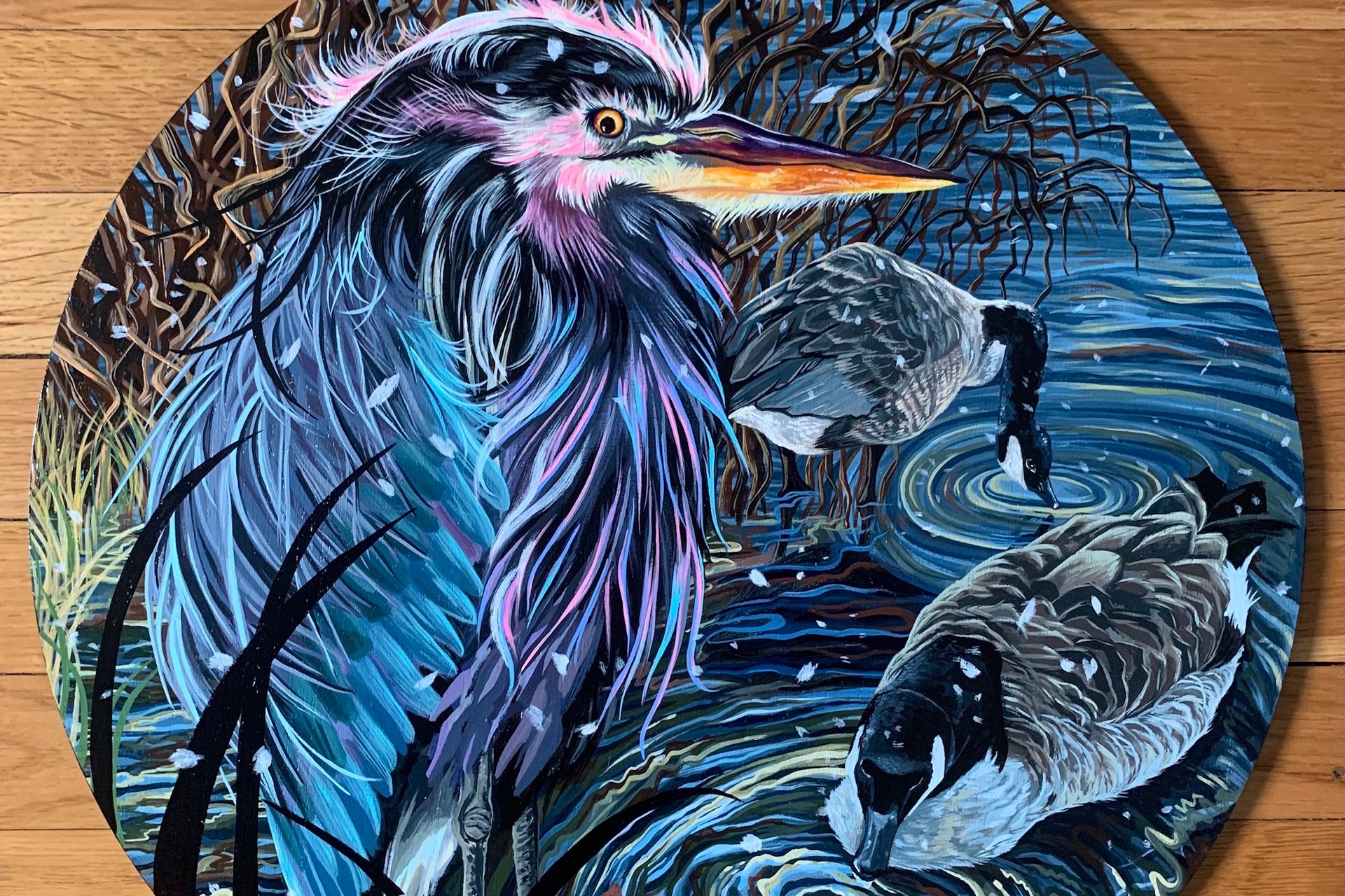 A blue-hued painting of a heron and two ducks on a round canvas