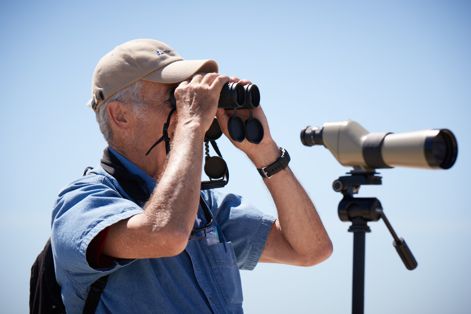 man with blue shirt looking through binoculars