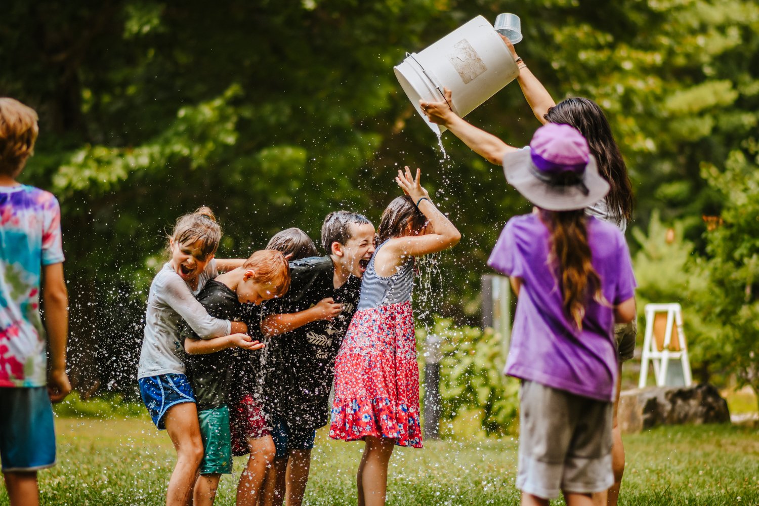 A group of campers gets doused with a bucket full of water by a counselor at Moose Hill Nature Camp