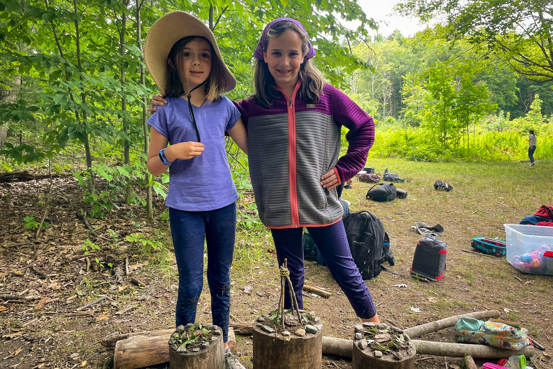 Two Berkshires campers smiling and showing off their art creations, made out of found objects in nature