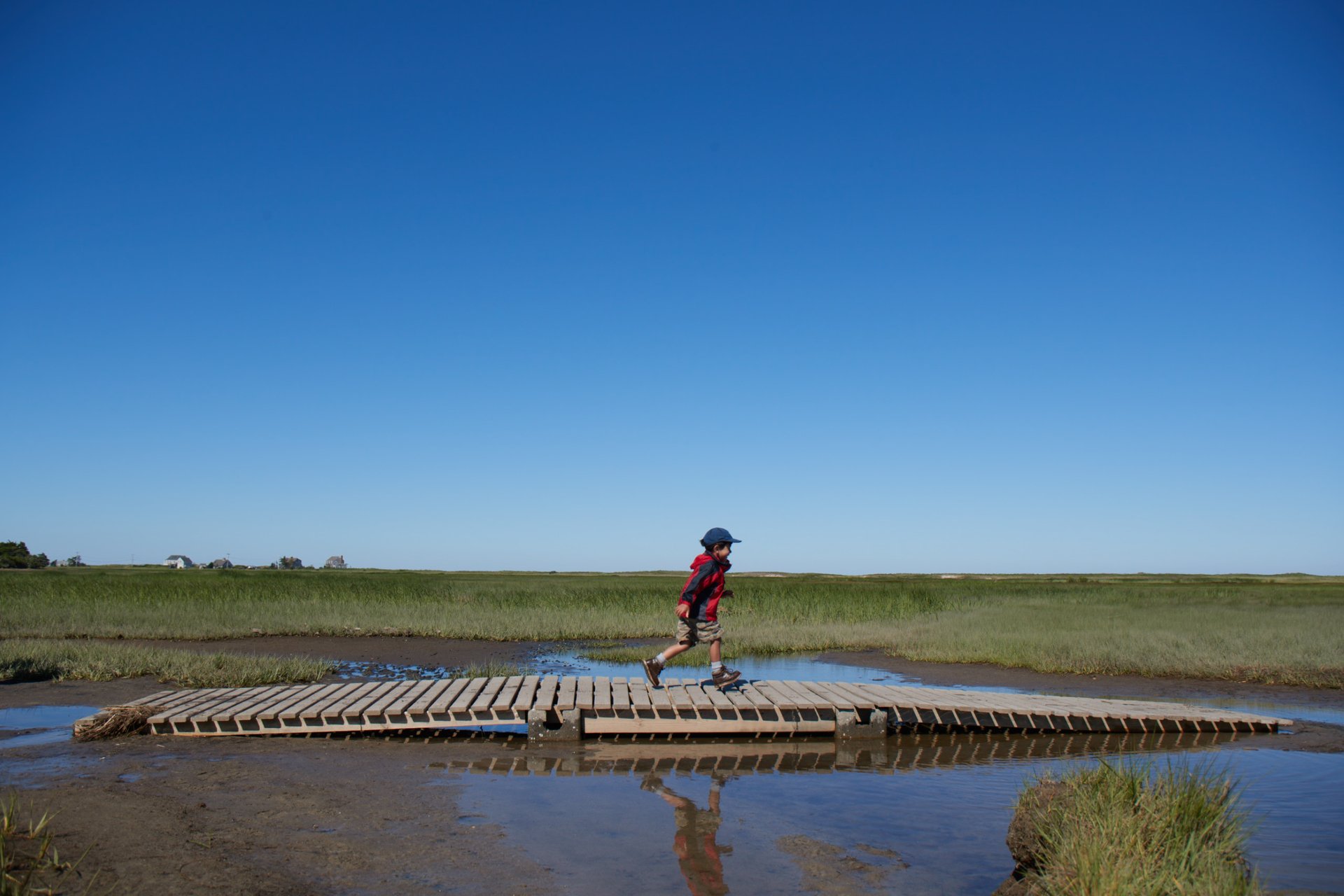 boy walking across boardwalk over flooded marsh