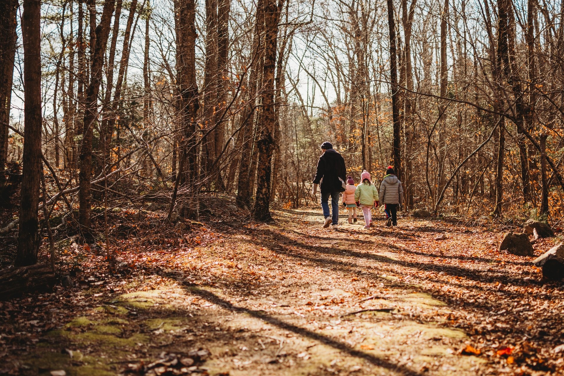 Family walking down trail surrounded by bare fall trees