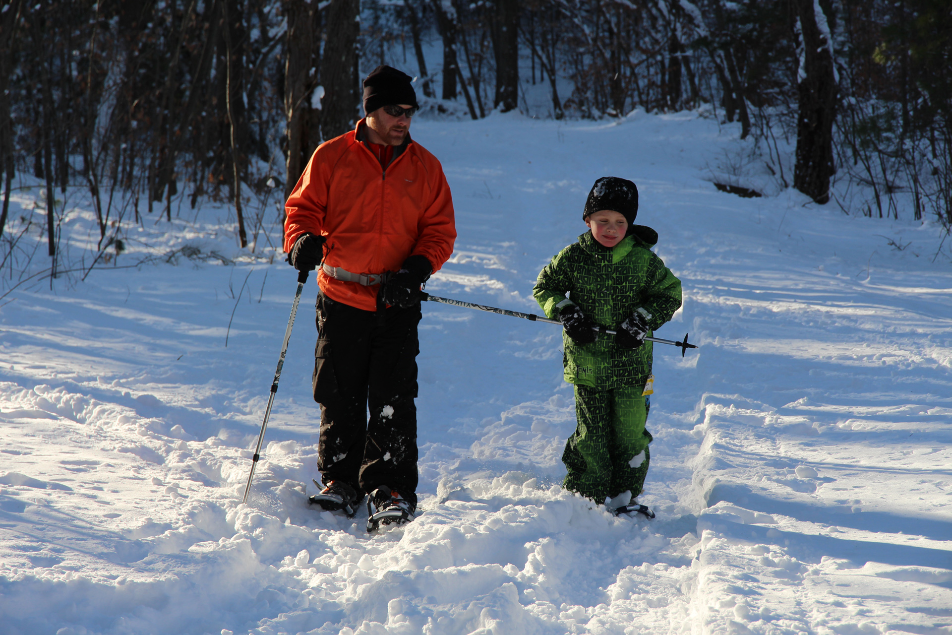 adult and child on snowshoes on a trail at Broad Meadow Brook