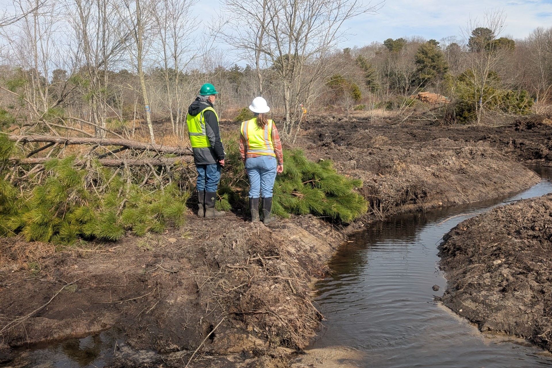 two people standing by degraded waterway