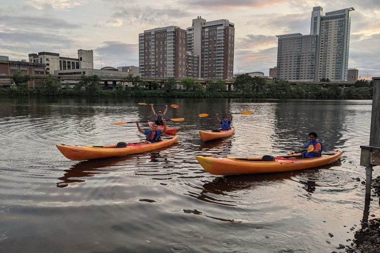 Four people in kayaks on the Charles River