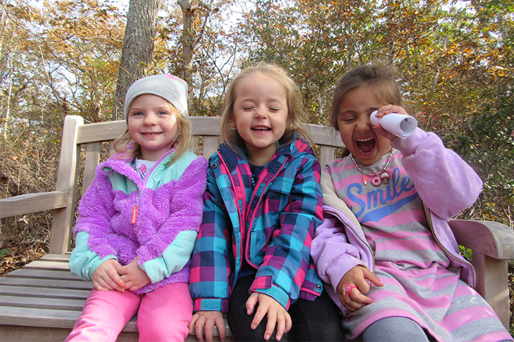 Three FN preschoolers laughing on a bench in fall 750