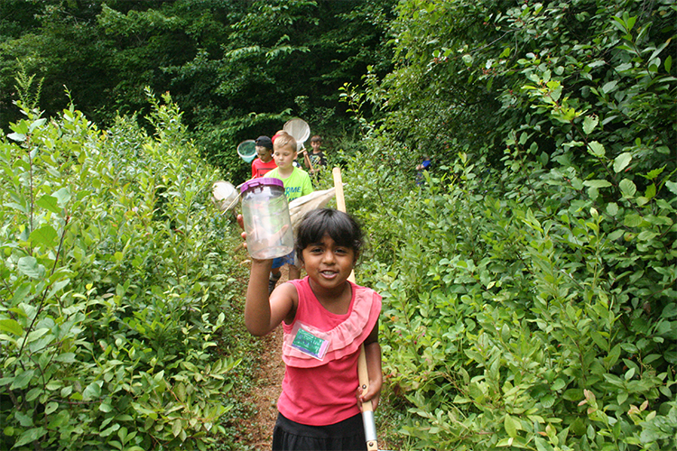 Oak Knoll camper proudly holding up a bug collection jar
