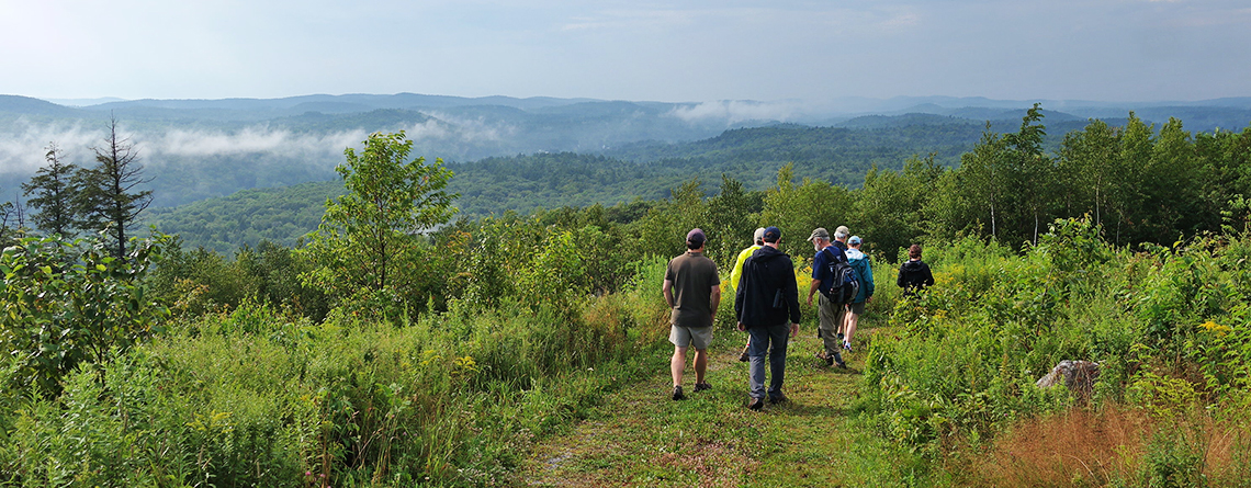 Group of hikers at trail summit of Old Baldy Wildlife Sanctuary in summer