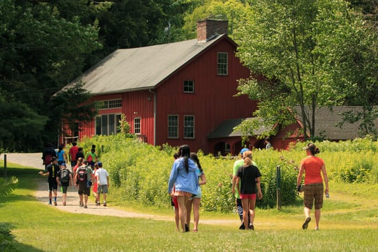 Students walking uphill along the path toward the nature center and red education barn at Pleasant Valley